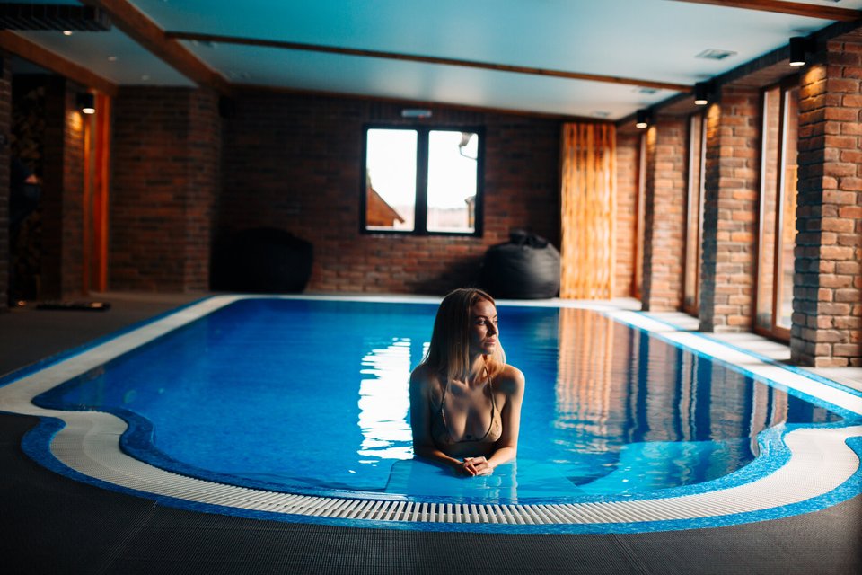Критий басейн у SPA, тепла цегляна кладка стін, блакитна вода з відблисками